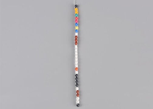 Column of multicolored seed beads showing thread emerging from both sides of each seed bead